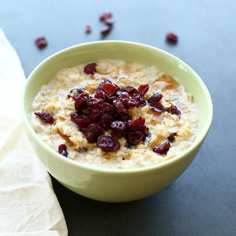 a bowl of Quaker oats porridge with cranberries and maple syrup on top