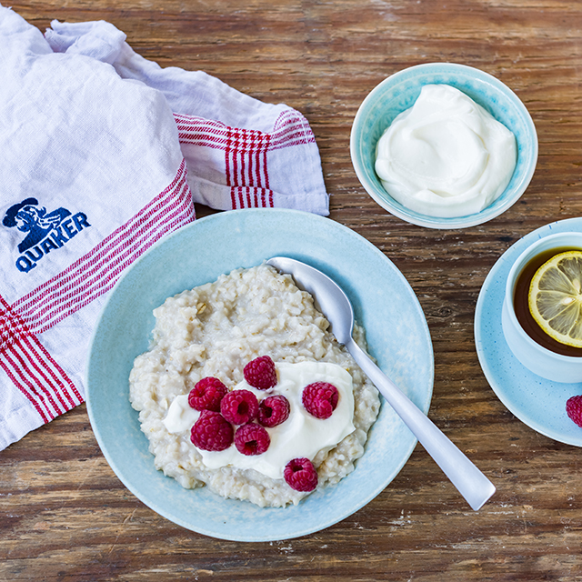 a bowl of Quaker oats porridge topped with raspberries and low-fat yogurt drizzled over the top