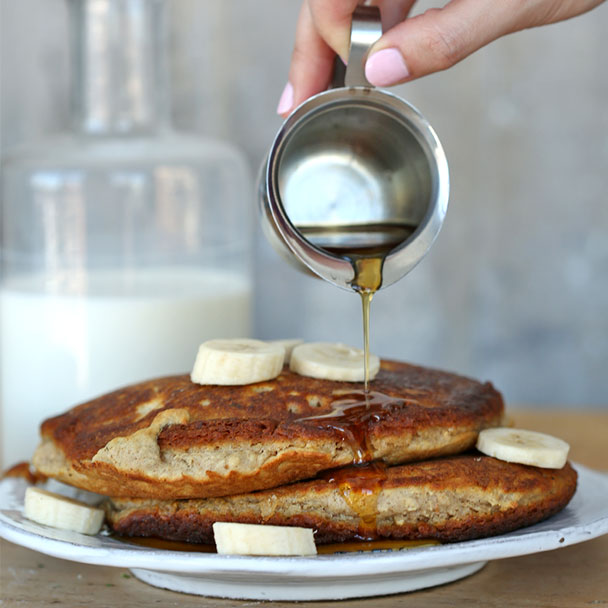 hearty banana oat pancakes served with warm syrup on a plate